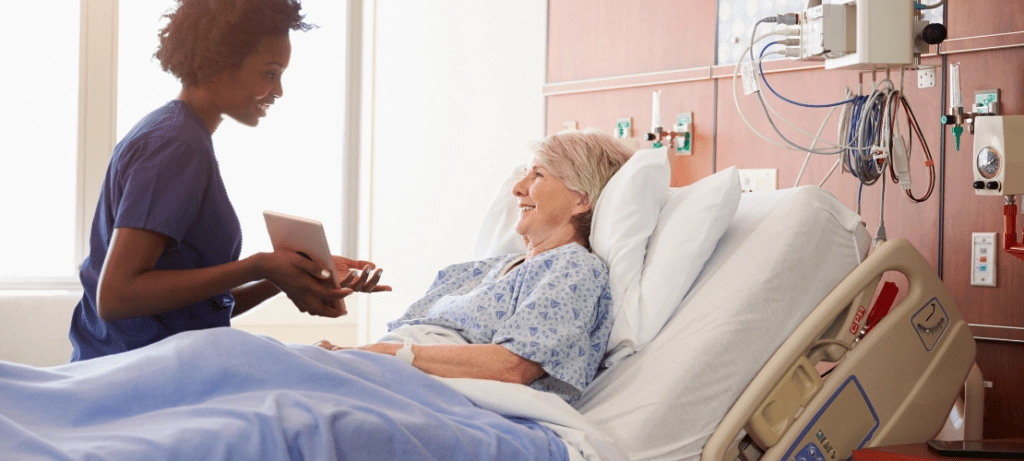 A nurse with a tablet speaks to a patient.