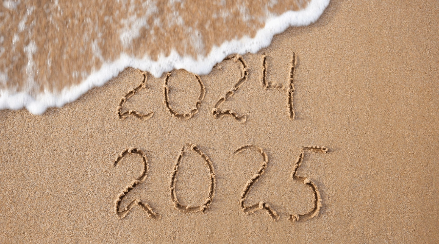 A beach wave washes out 2024 written in the sand.