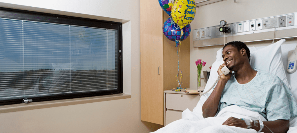 A hospital patient speaks on the phone while recovering in his room.