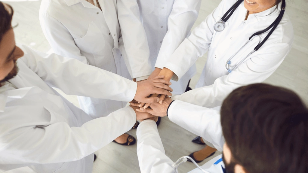 A medical team joins hands in a show of collaboration and process standardization.