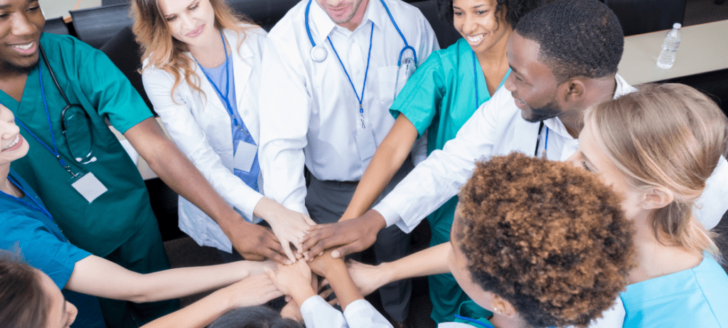 A hospital care team joins hands.