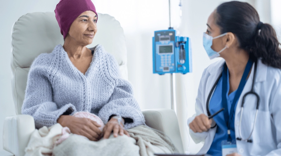 A cancer patient getting chemo speaks with a doctor.
