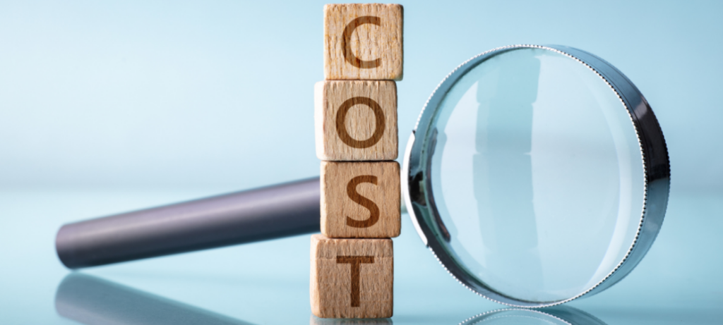 A magnifying glass and the word "cost" spelled out in wooden blocks.