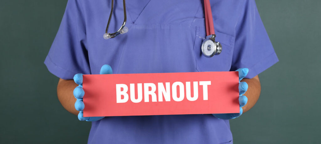 Medical professional holding a sign that reads, "BURNOUT."